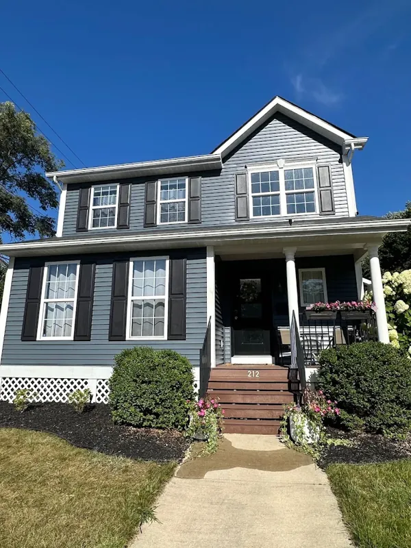 Two-story blue-gray home with crisp white trim, black shutters, and a freshly painted front porch.