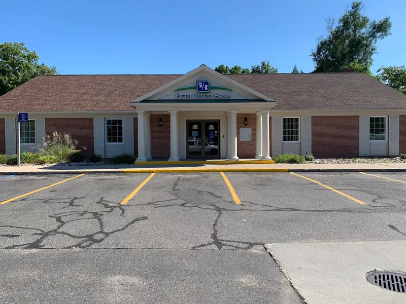 Brick commercial building with a red roof, white trim, and a freshly striped parking lot.