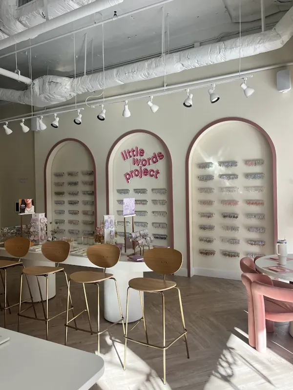 Retail boutique interior with arched display niches, pink accents, and wood stools.