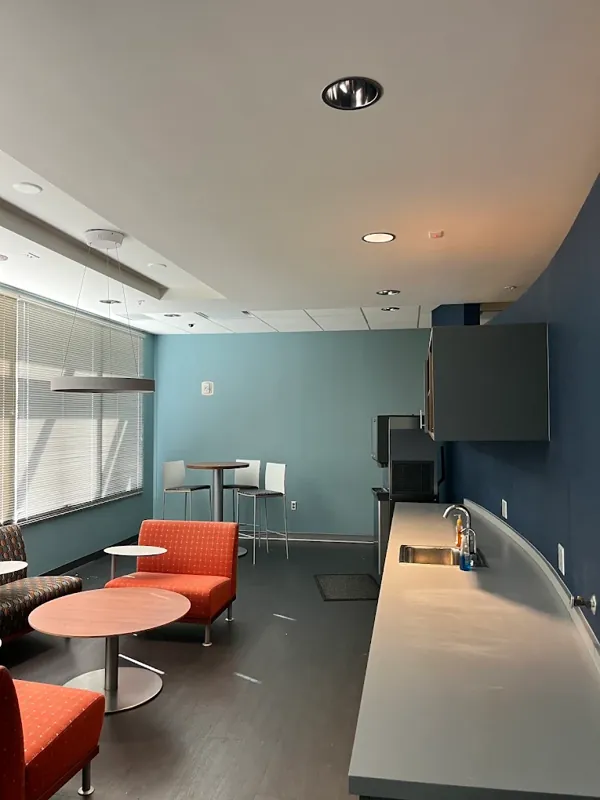 Office break room with a blue accent wall, orange chairs, and a round table.
