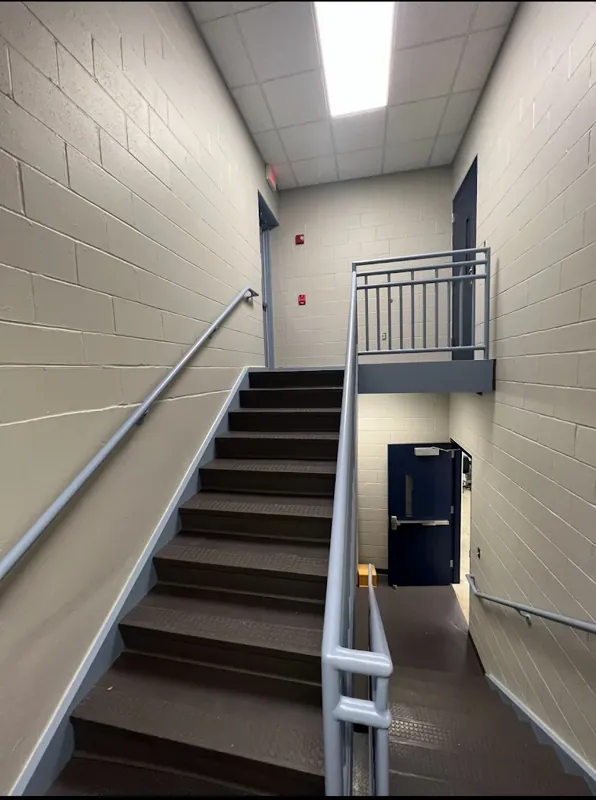 Commercial stairwell with painted gray block walls and a dark metal railing.