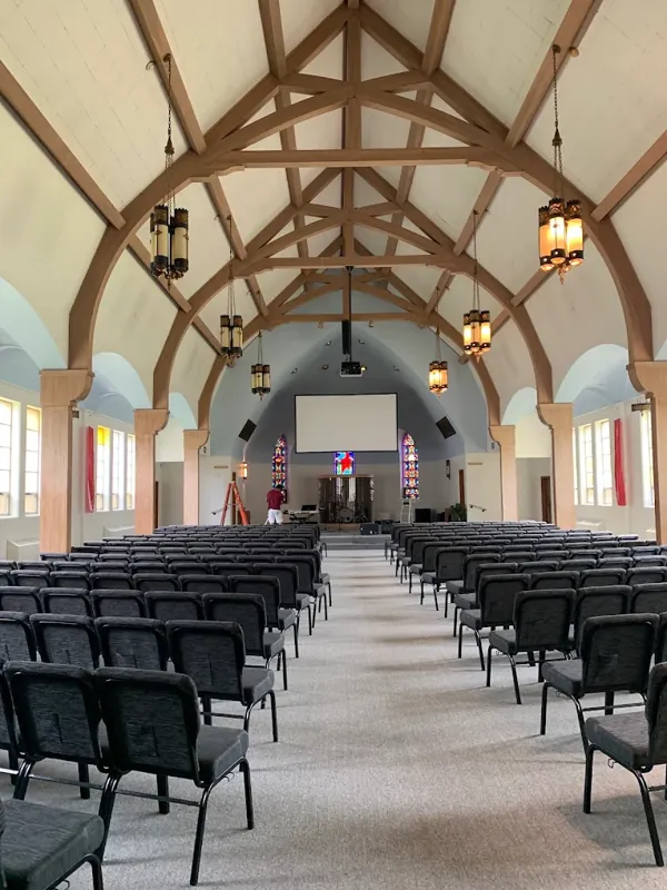 Church sanctuary with a vaulted ceiling, wood trusses, and freshly painted walls.