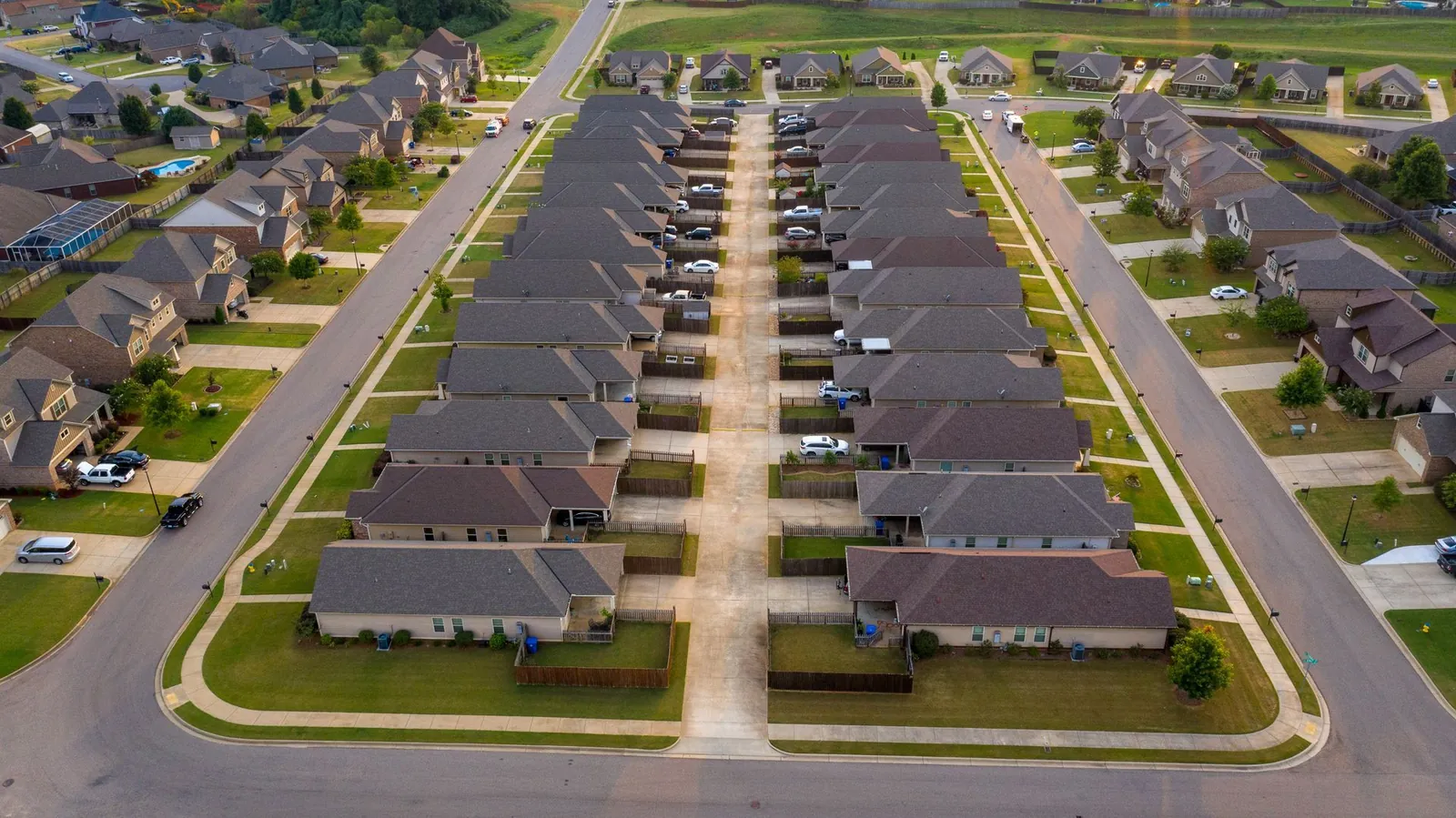 Aerial view of a suburban neighborhood with two rows of houses facing a shared central driveway.