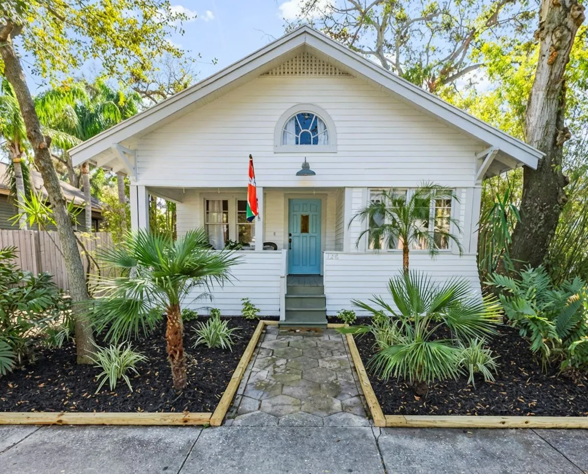 Exterior house painting on a Tampa bungalow with white siding and blue accent door