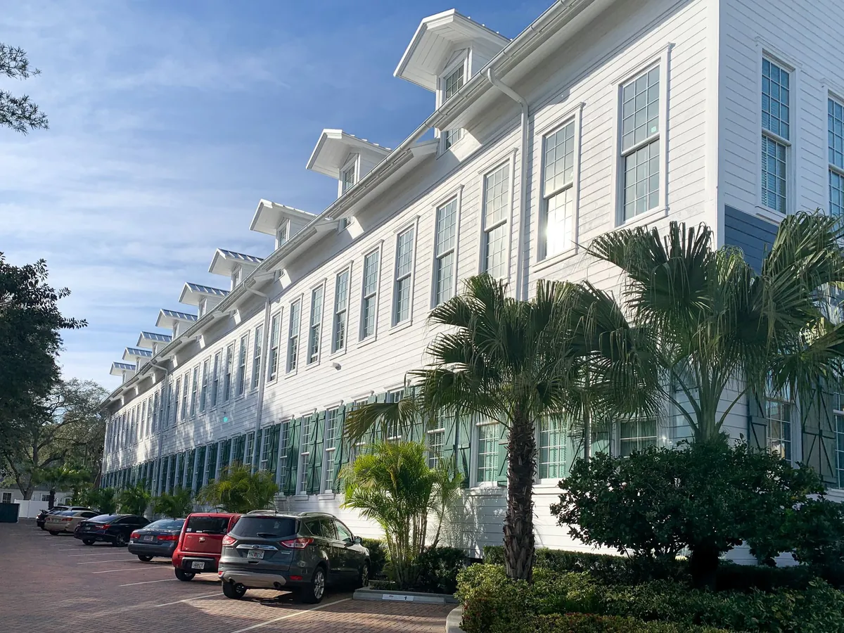 Large scale commercial exterior painting on multi-unit residential building in Tampa with white siding and green shutters
